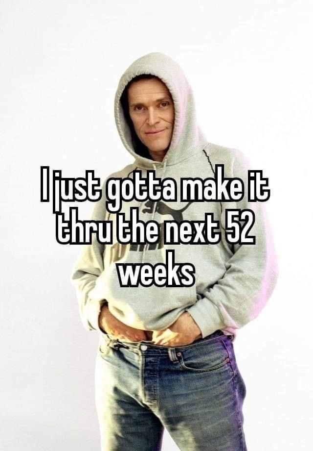 Willem Dafoe poses in a gray hoodie and jeans with his hands in the waistband, a confident smirk on his face. Text overlays the image: "I just gotta make it thru the next 52 weeks."